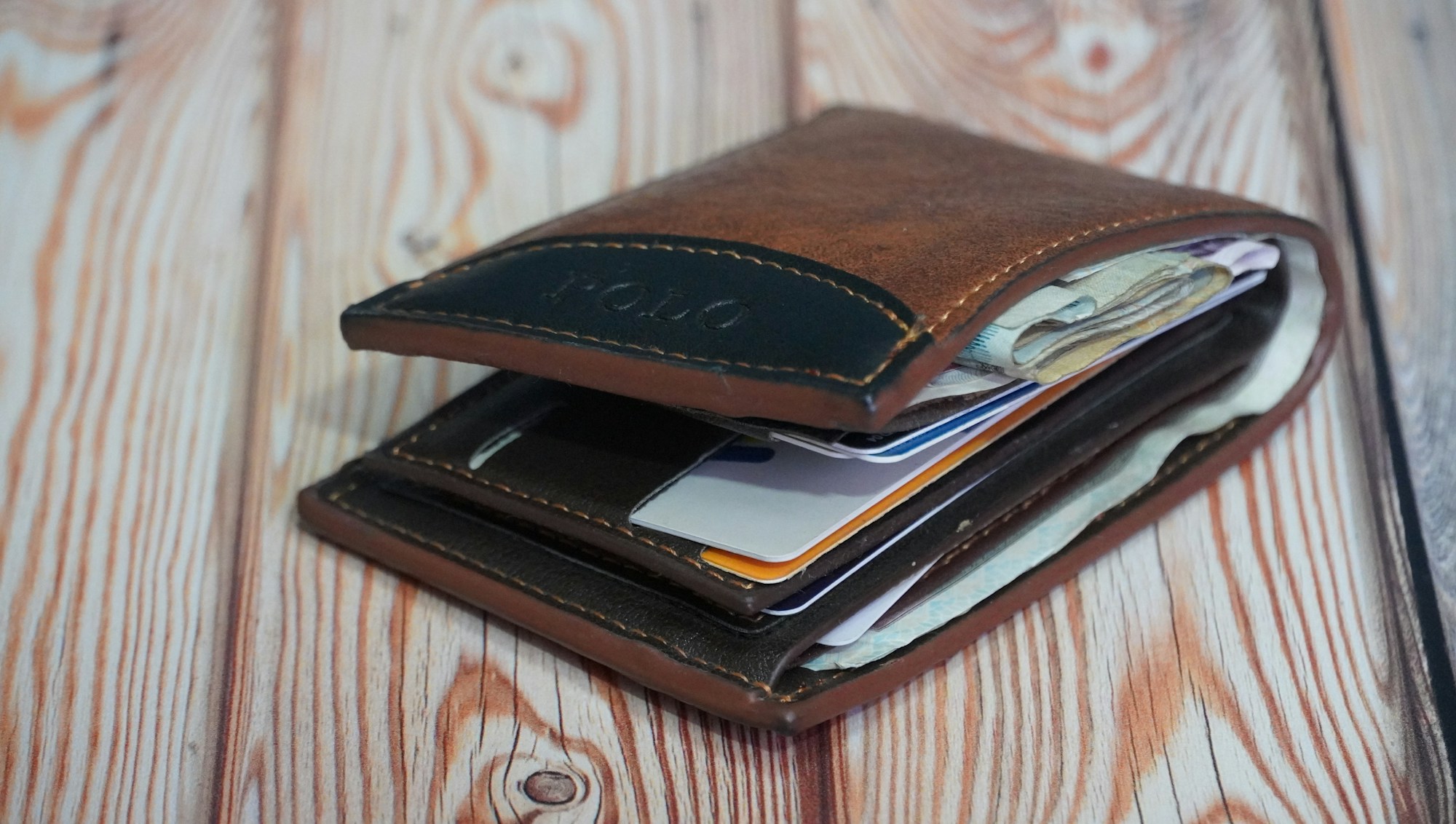 An open leather wallet with a credit card on a wooden table